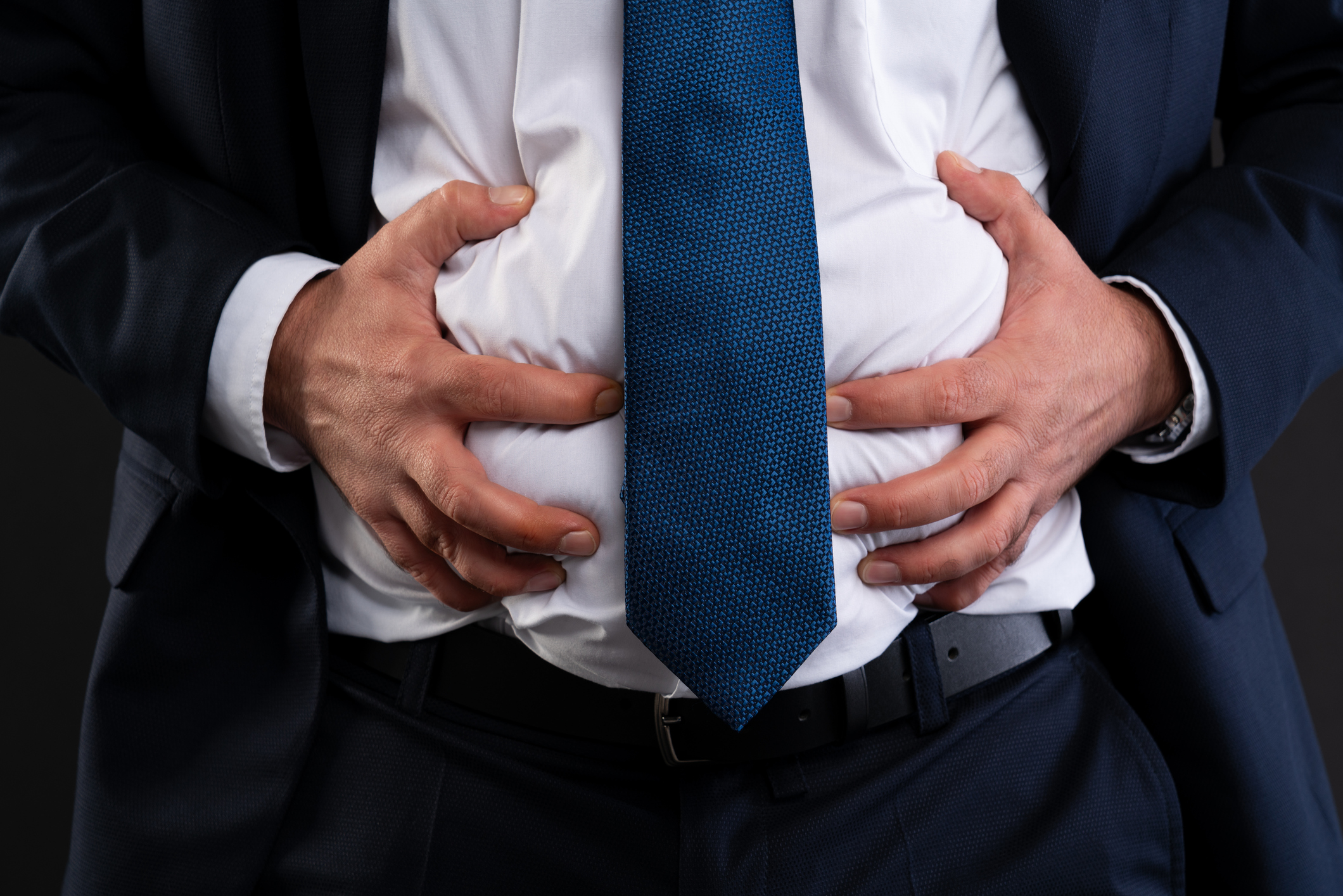 Close-up of hands pressing bloated stomach